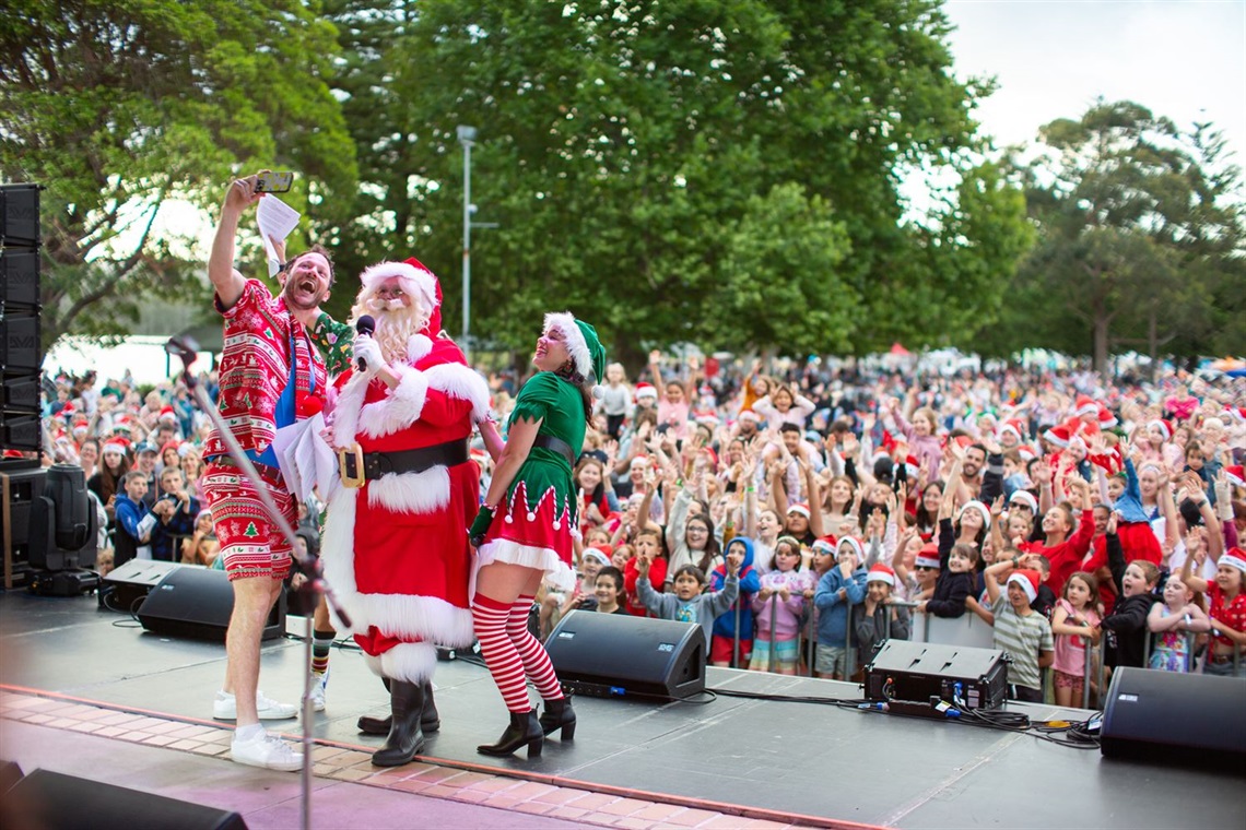 Hosts Nick, Jess, Ducko and Santa take a selfie in front of the Lake Mac Carols crowd.jpg