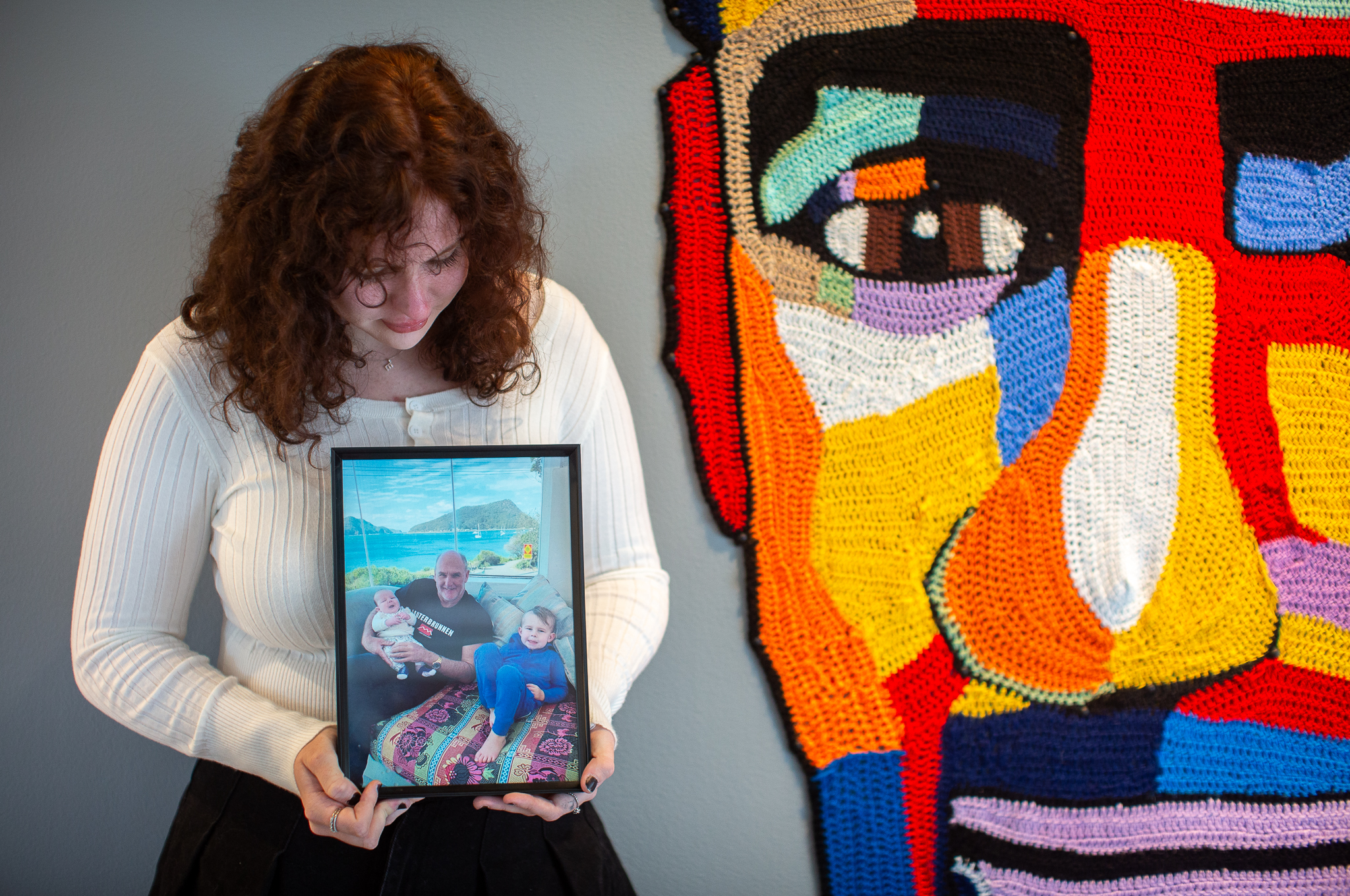 Artist Elle Vitnell with the crocheted portrait of her late father, David, and a photo of him at home in Port Stephens.jpg